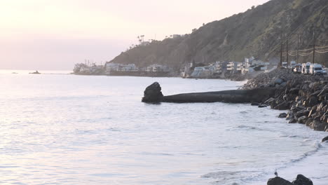Serene-nostalgia-on-the-beach-of-Big-Rock-Malibu,-next-to-a-highway-edge-road-at-golden-hour