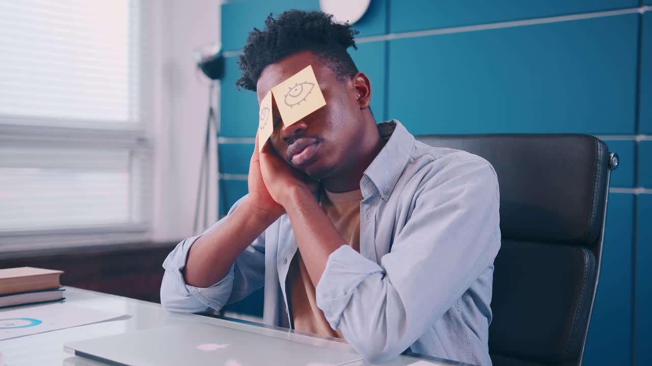 African american male napping while sitting at work table with laptop