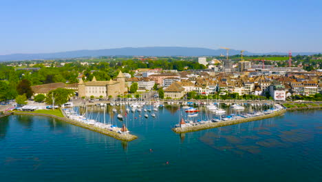 Barcos-En-El-Puerto-Cerca-De-La-Ciudad-Costera-De-Morges-En-La-Orilla-Del-Lago-De-Ginebra-En-Vaud,-Suiza---Drone-Aéreo