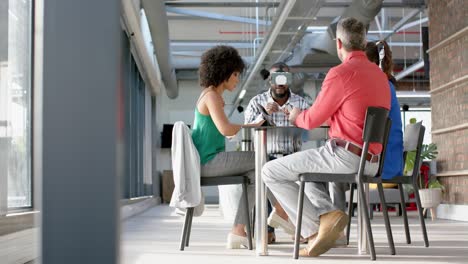 african american businessman wearing vr headset, gesturing while colleagues watching him at office