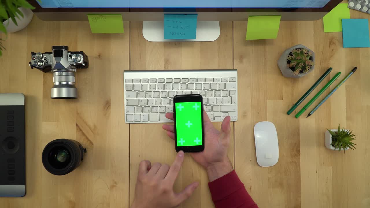 colocación plana de las manos del hombre usando el teléfono con pantalla verde en el lugar de trabajo