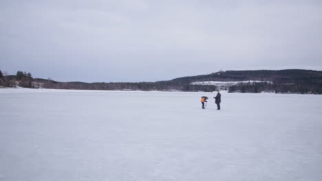 panning shot across holiday club katinkulta, vuokatti, finland hikers standing on frozen woodland lake