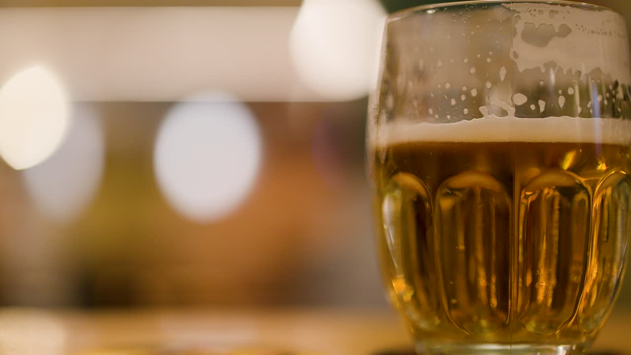 Closeup of foamy lager beer mug on table, cozy brewpub atmosphere in Pilsen, Czech Republic