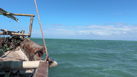 a wooden boat sails on a calm ocean with a blue sky and white clouds