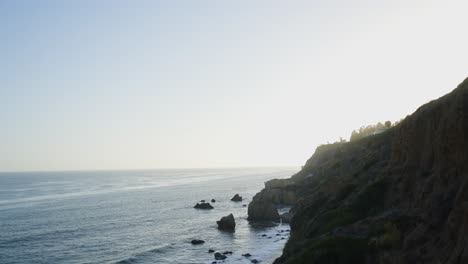 golden hour view of rugged cliffs and sea stacks along the pacific coast, with calm waters stretching to the horizon