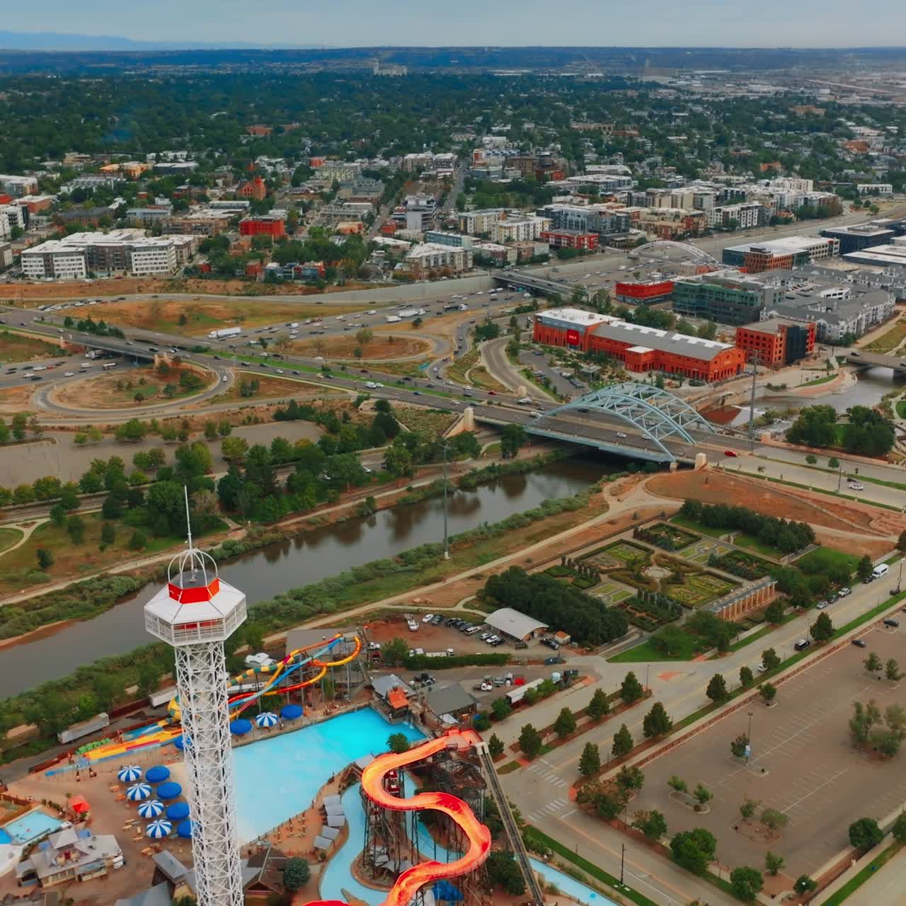 Flying above Elitch Gardens amusement park and South Platte River in Denver, Colorado, USA. Panorama of big lively city with busy traffic. Top view