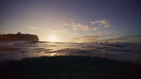 el agua se derrama por delante mientras la luz del sol proyecta la luz de la mañana sobre los surfistas en el descanso