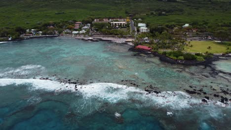 toma de zoom de dron cinematográfico de 4k de aguas azules profundas y olas rompiendo en la playa en la playa de arena negra de kahalu'u en kona en la isla grande de hawaii