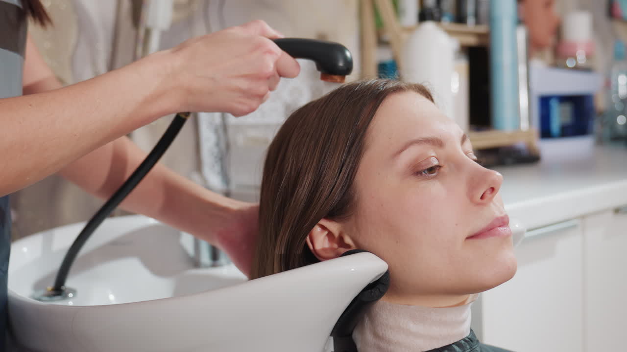 고급 헤어 케어, 고객이 고급 샴푸와 액세서리로 편안하게 머리를 감는 모습, 세심한 스타일리스트가 고객 관리 중에 고급 제품을 사용하는 우아한 살롱 풍경