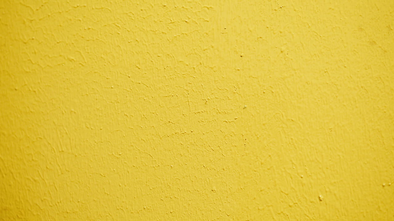 Close-up of Hand Painting a Yellow Wall with a Paint Roller