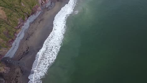 Toma-Aérea-De-Olas-Blancas-Rompiendo-En-La-Orilla-De-La-Costa-De-Cobre-Waterford-Irlanda