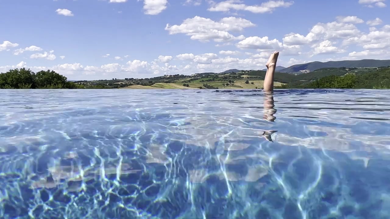 Frau schwimmt in einem Infinity-Pool mit Blick auf die Landschaft.
