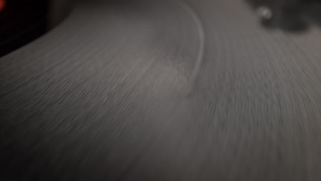 surface of spinning vinyl record on the platter of a wooden turntable, top view