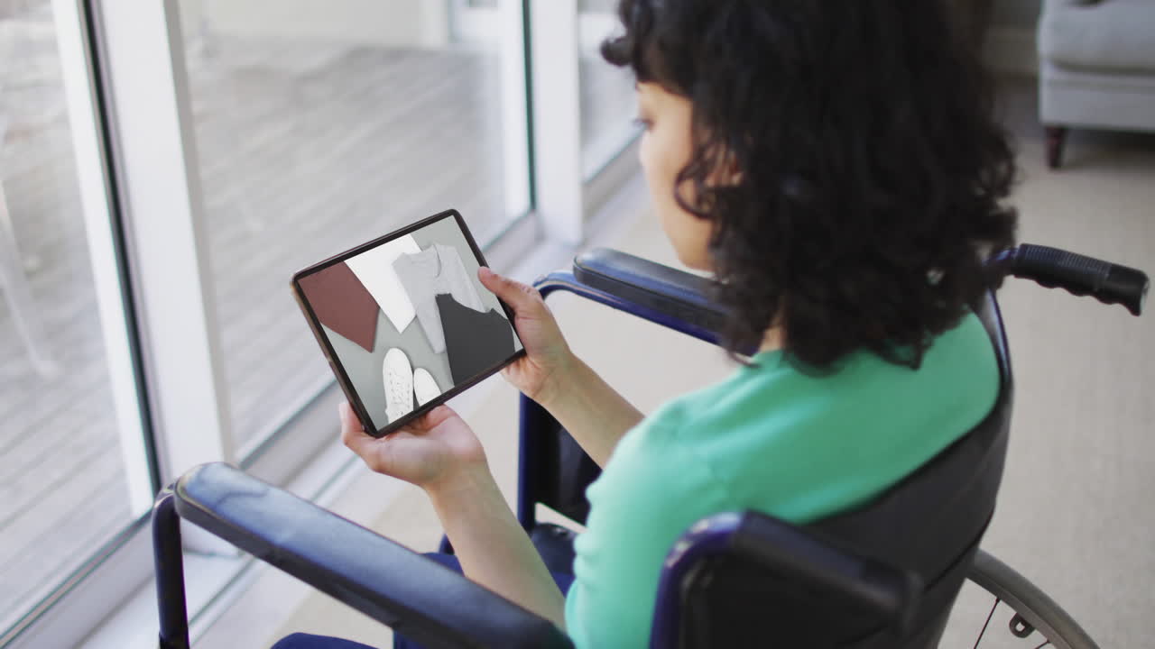 Donna birazziale in sedia a rotelle che usa un tablet, fa shopping online per vestiti, al rallentatore