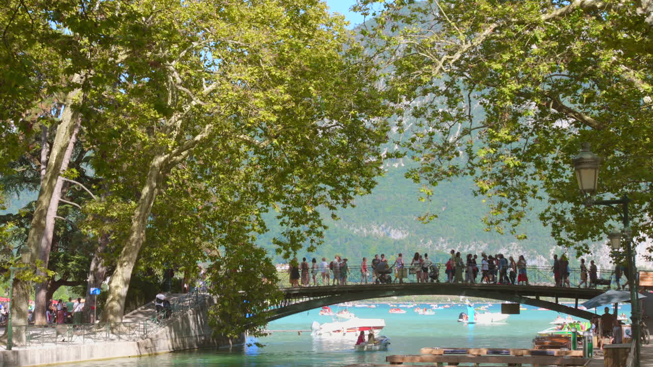 Crowd of tourists taking photographs of Canal du Vassé from Annecy love bridge in Annecy, France.
