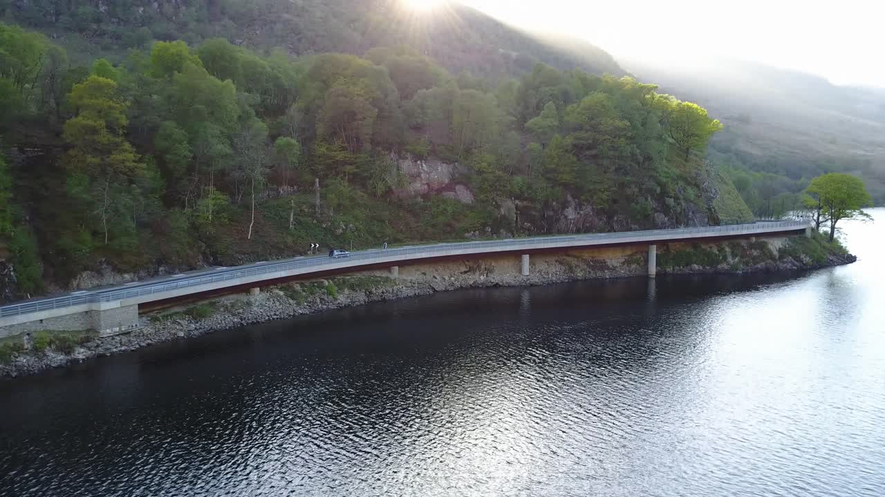 스코틀랜드 호숫가를 따라 탁 트인 도로를 달리는 자동차