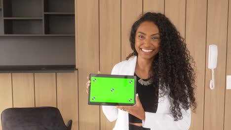 Schöne-Schwarze-Frau-Hält-Tablet-Mit-Grünem-Hintergrund-Und-Lächelt-Horizontal