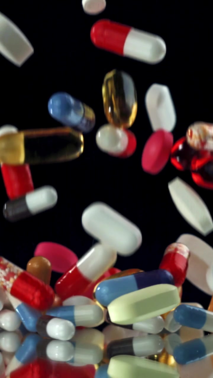 Colorful Pills and Capsules Falling in Slow Motion on Black Background