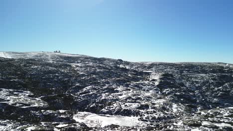 retroceso aéreo del paisaje rocoso nevado desde la cumbre de serra da estrela, portugal