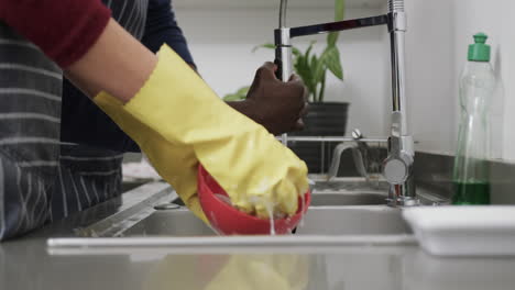 Diverse-couple-washing-up-in-kitchen,-slow-motion,-copy-space