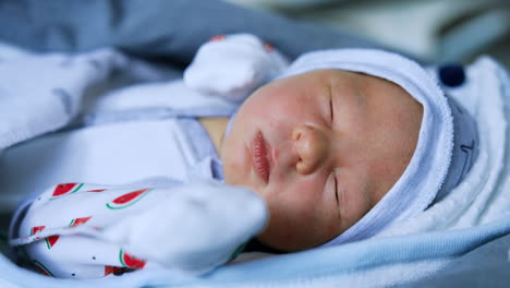 angelic newborn baby in little cap lies on his back. cute child sleeping peacefully. close up.