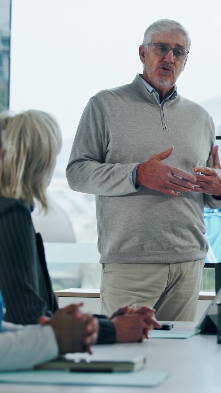 Senior Businessman Giving a Presentation to Colleagues in an Office