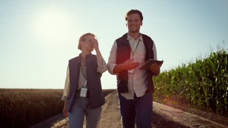 agricultores sonrientes caminando por las tierras de cultivo en un día soleado. equipo agrario feliz en el campo.