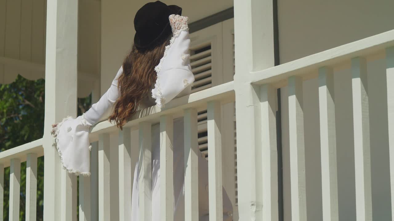 A bride-like young woman in a retro wedding dress gazes out from a historic stronghold.