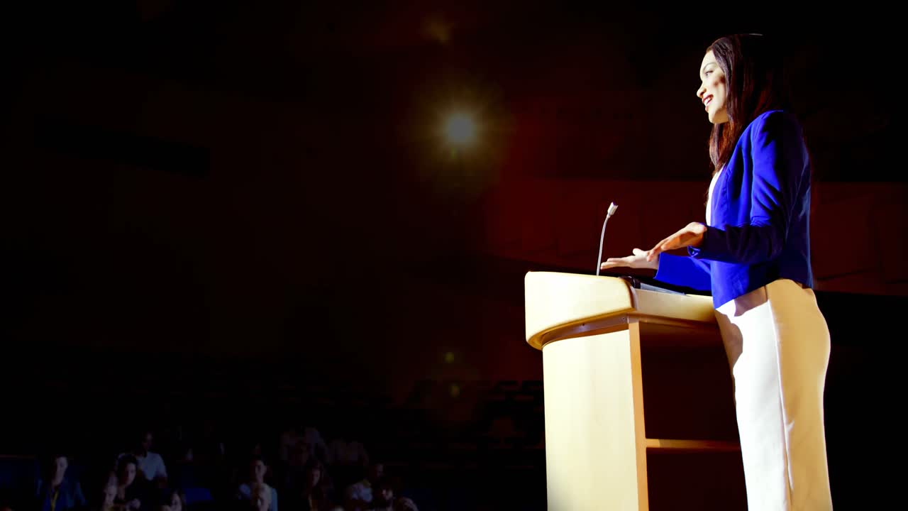 joven mujer de negocios de raza mixta hablando en un seminario de negocios en el auditorio 4k
