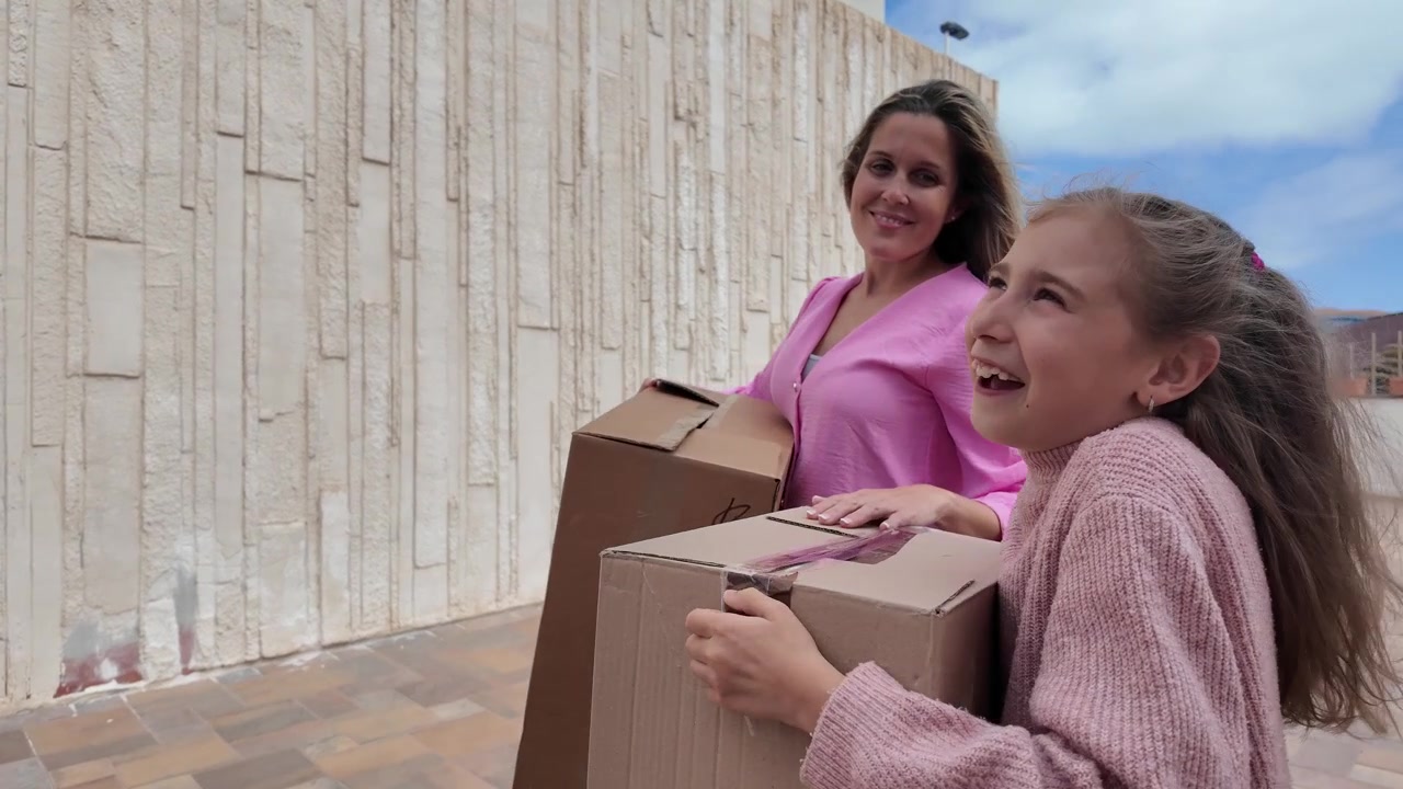 Mother and Daughter Entering New Home Carrying Moving Boxes