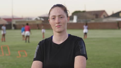 portrait of young adult female rugby player on a rugby pitch