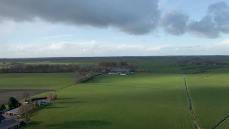 flying towards a distant farm surrounded by green meadows
