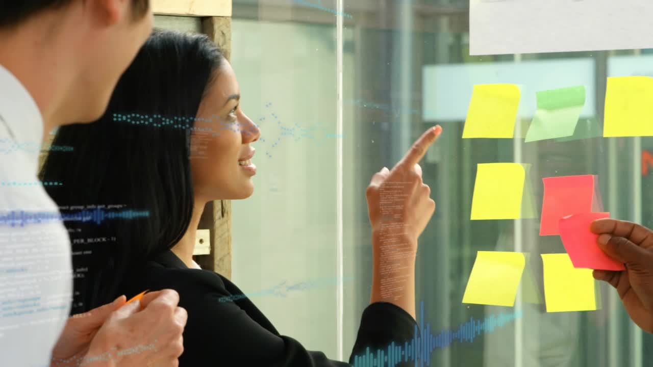 Woman speaking and pointing at yellow note on glass, man offering pad, overlay marking biz priority