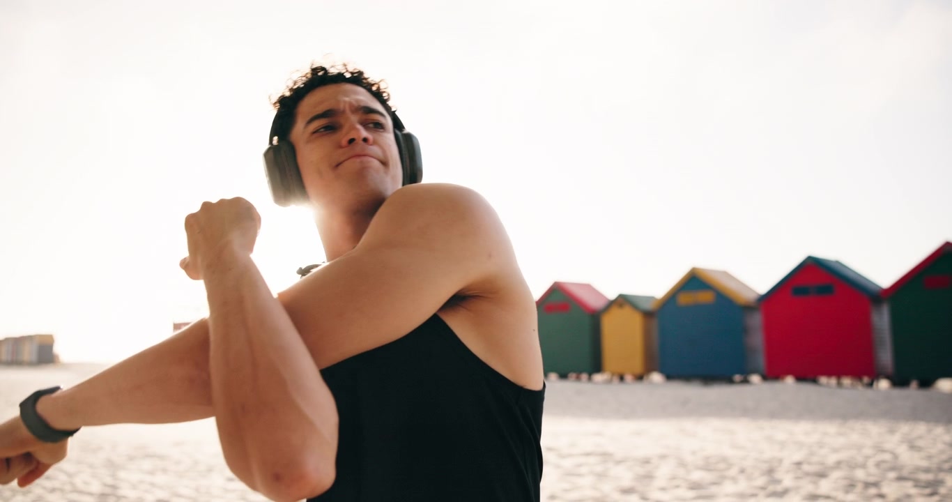 Athletic Man Stretching Arms on Beach Before Workout