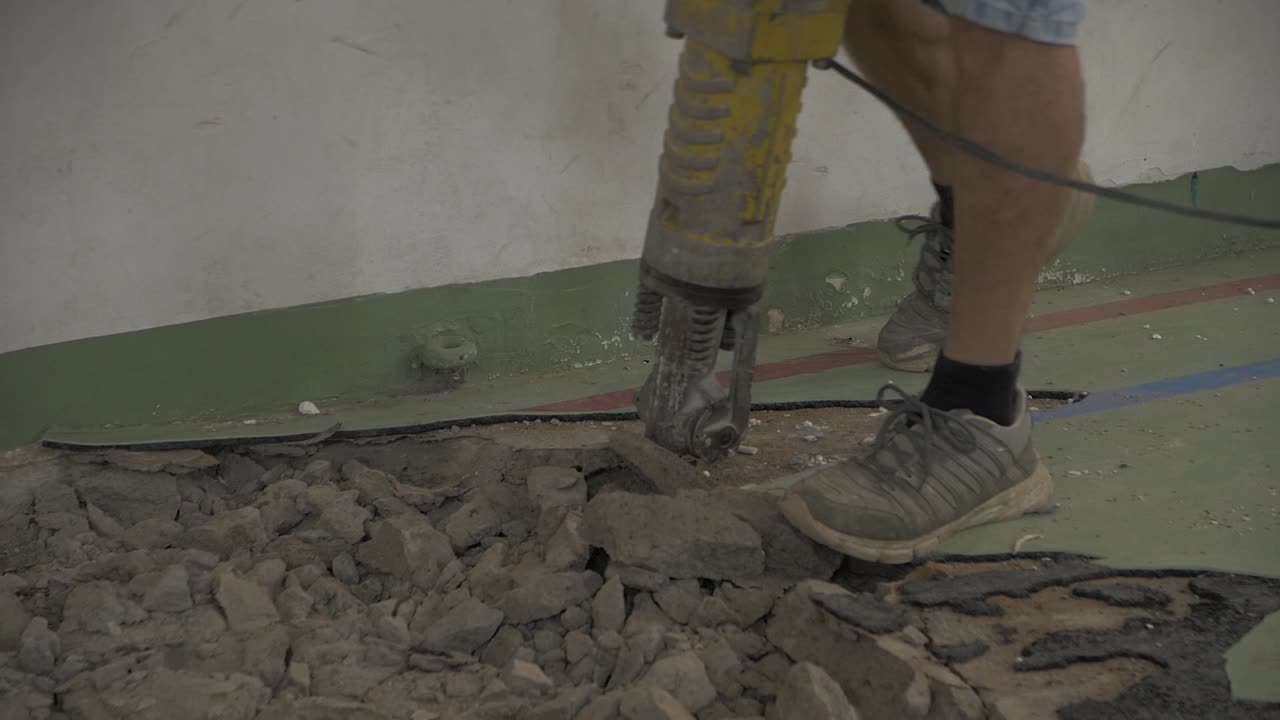 hombre con un martillo rompiendo un piso de hormigón