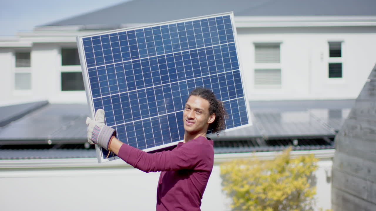 retrato de un hombre feliz de dos razas con guantes llevando un panel solar en el jardín, cámara lenta