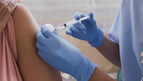 Mid-section-of-african-american-female-doctor-giving-an-injection-to-senior-woman-at-home