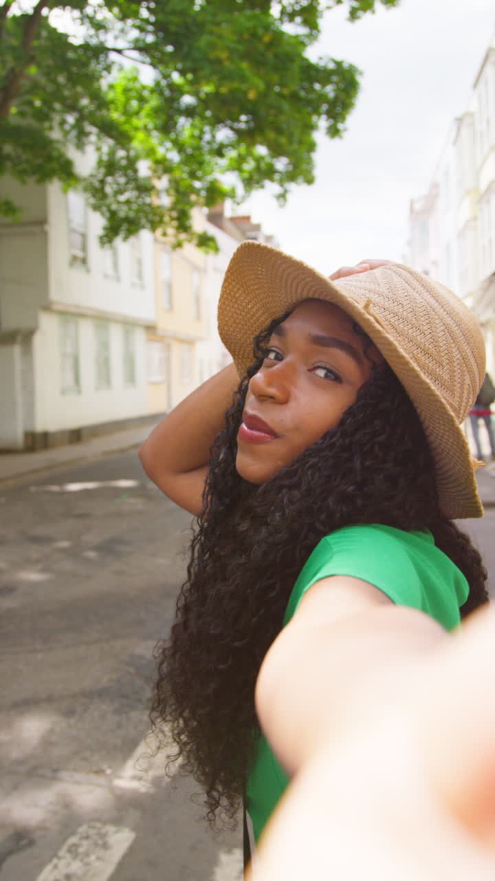 Vertical Video POV Shot Of Female Tourist On Vacation In Oxford UK Exploring City Walking Along Holywell Street Posing For Selfie On Mobile Phone 2