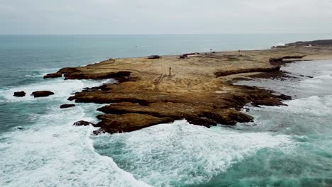 vista aérea de las olas del océano salpicando en los acantilados oscuros