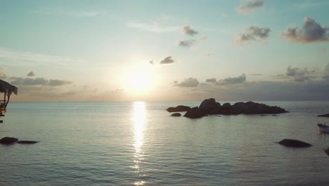 impresionante puesta de sol sobre el océano con rocas y un pequeño barco