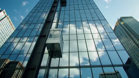 a stunning perspective of a modern glass building capturing reflections of clouds amidst a vibrant urban skyline