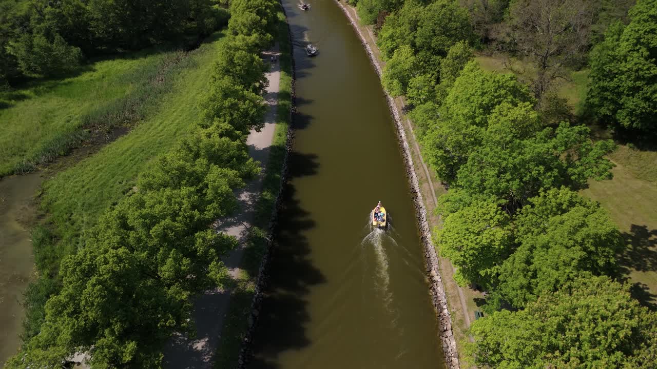 Aerial view following a boat passing two other boats on a tight canal in Djurgården.