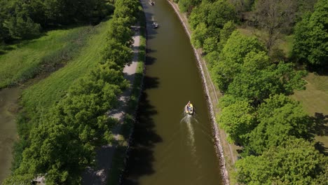 aerial view following a boat passing two other boats on a tight canal in djurgården.