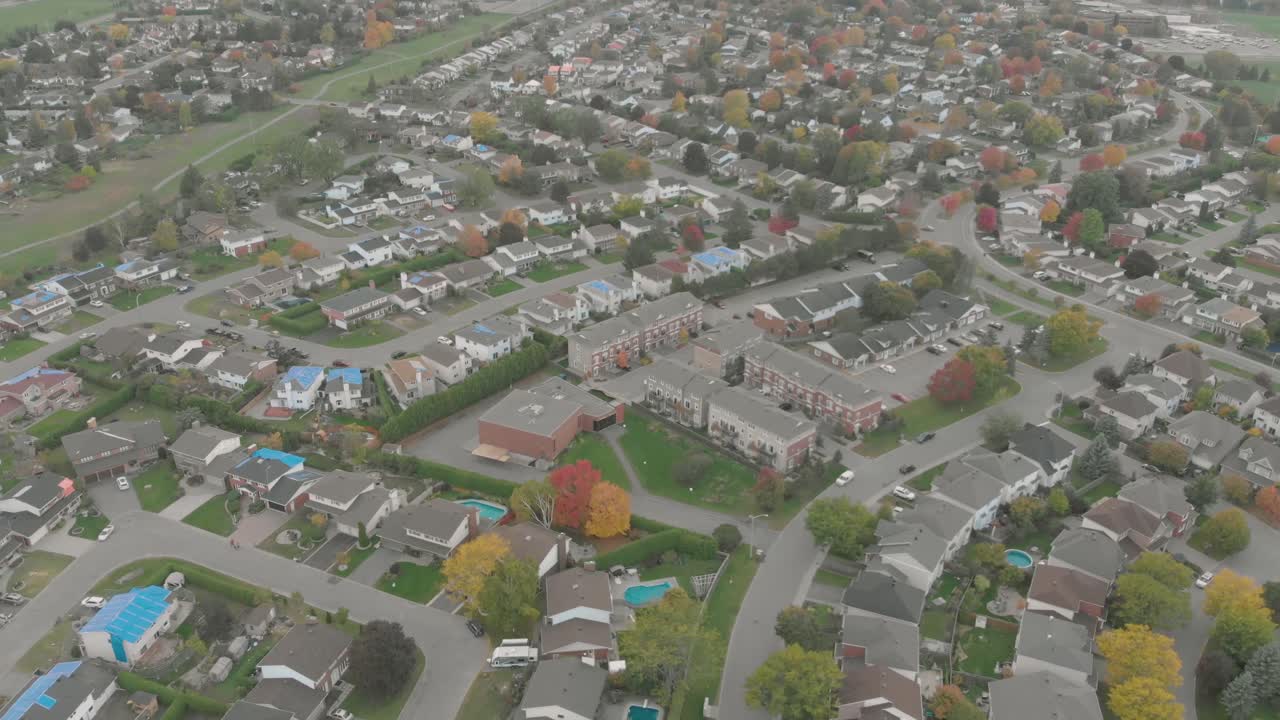 toma aérea inversa que sube desde una vista de un apartamento hasta la vista de una enorme puesta de sol con rayos de sol disparando a través de nubes hinchadas sobre un pequeño y agradable vecindario