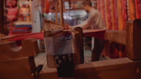 Close-up-young-man-weaves-wool-into-textile-using-manual-machine-in-a-family-shop-in-Fes-Morocco