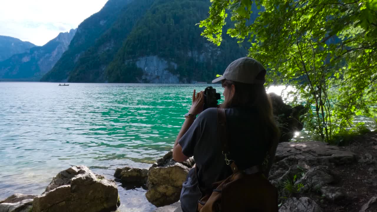 Tourist woman taking a photo with a camera in the shore of the King's Lake, K&ouml;nigssee in Germany, Bavaria