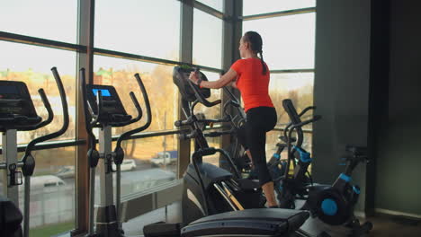 cute young brunette doing thigh exercises on the simulator. modern simulators near the panoramic window.