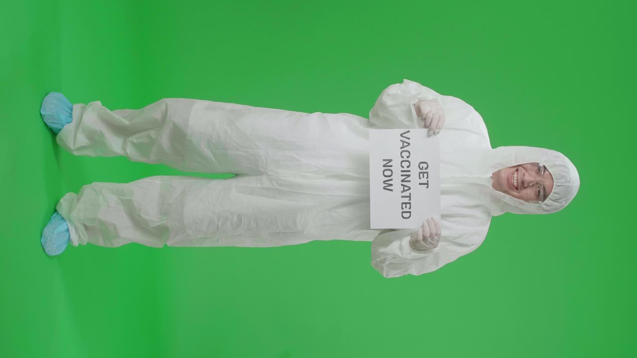 Full Body Of Asian Man Wearing Personal Protective Equipment Uniform Ppe And Holding Get Vaccinated Now Sign In The Green Screen Studio