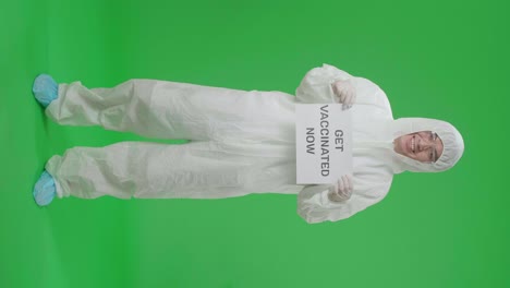 full body of asian man wearing personal protective equipment uniform ppe and holding get vaccinated now sign in the green screen studio