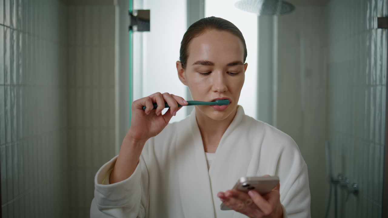 Model daily cleaning teeth using smartphone closeup. Pretty woman doing dental